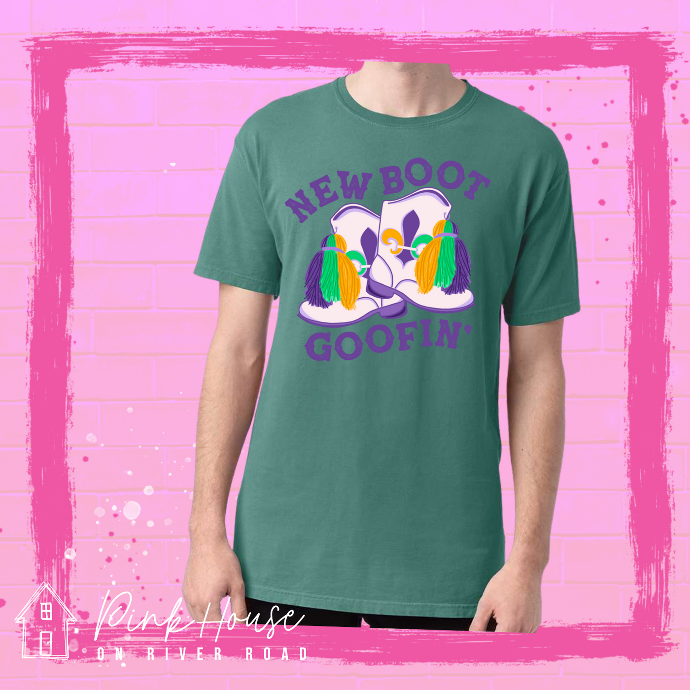 A seafoam green tee with a graphic. Graphic is of a pair of majorette boots, the boots have a tassel and fleur de lis both in gold, green and purple. the words New Boot are above the boots and the word goofin' is below thee boots the words are in purple.