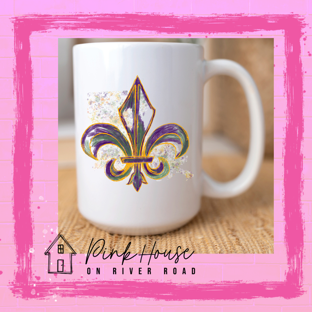 A white coffee mug with a Fleur De Lis. The Fleur De Lis is gold, green, and purple sketch style laid on top of a gold, green, and purple splatter state of Louisiana.