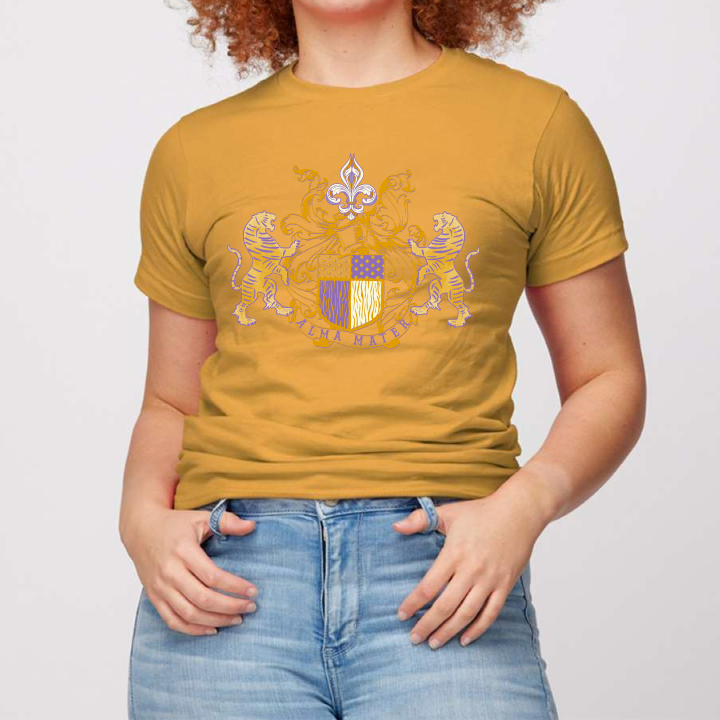 LSU Gold Tee. Alma Mater Classic family crest style hand drawn design. Crest has a tiger on each side with a banner below that reads Alma Mater with a fleur de Lis with filigree on top. Design is in LSU Purple and Gold