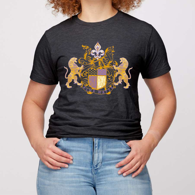 Heather Black Tee. Alma Mater Classic family crest style hand drawn design. Crest has a tiger on each side with a banner below that reads Alma Mater with a fleur de Lis with filigree on top. Design is in LSU Purple and Gold