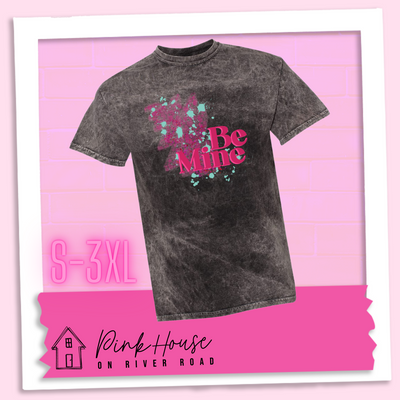 Black Mineral Wash Tee with a squiggle design made of pink hearts and pink sparkles with light teal splatters and pink text at the end of the art that says Be Mine with a hot pink shadow.