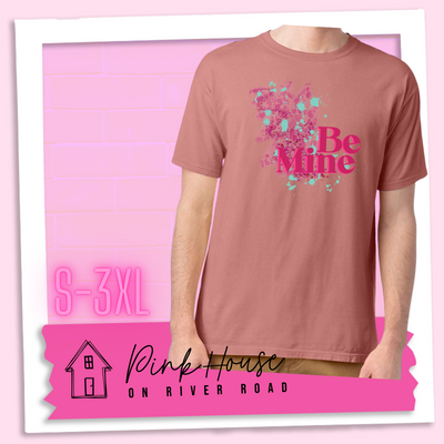 Mauve Tee with a squiggle design made of pink hearts and pink sparkles with light teal splatters and pink text at the end of the art that says Be Mine with a hot pink shadow.