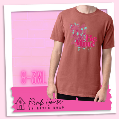 Nantucket Red  Tee with a squiggle design made of pink hearts and pink sparkles with light teal splatters and pink text at the end of the art that says Be Mine with a hot pink shadow.