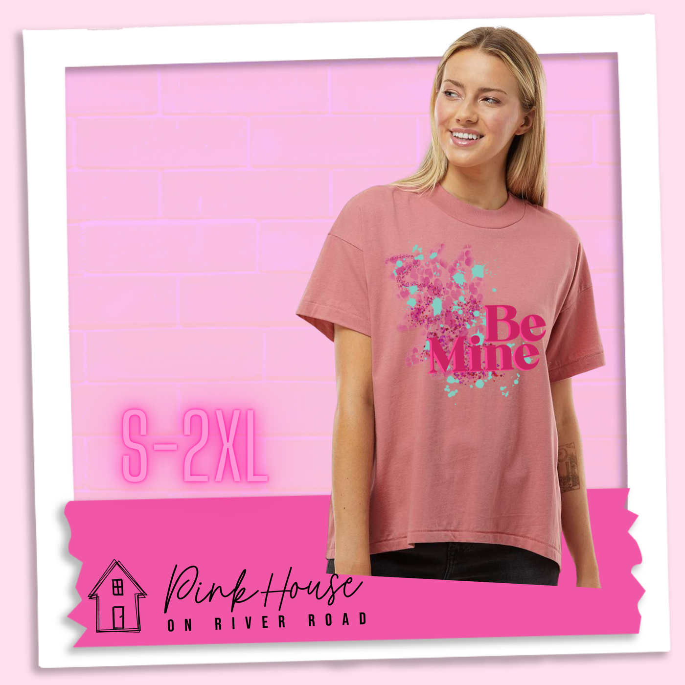 Blonde woman in a Mauve Oversize HiLo Tee with a squiggle design made of pink hearts and pink sparkles with light teal splatters and pink text at the end of the art that says Be Mine with a hot pink shadow.
