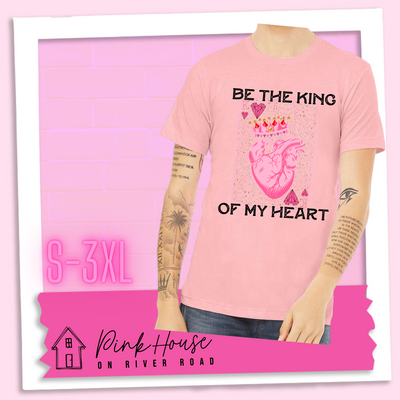 Pink Jersey Tee with a graphic that says "Be The King Of My Heart" in Black writing with a vintage effect. There is a King PLaying card with a speckled background, geometric hearts in the corners with the K and a realistic heart with a crown on it in the middle of the playing card.