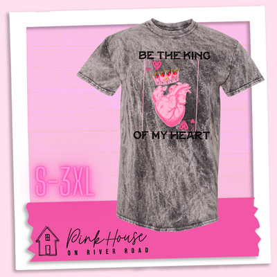 Charcoal Mineral Wash Tee with a graphic that says "Be The King Of My Heart" in Black writing with a vintage effect. There is a King PLaying card with a speckled background, geometric hearts in the corners with the K and a realistic heart with a crown on it in the middle of the playing card.