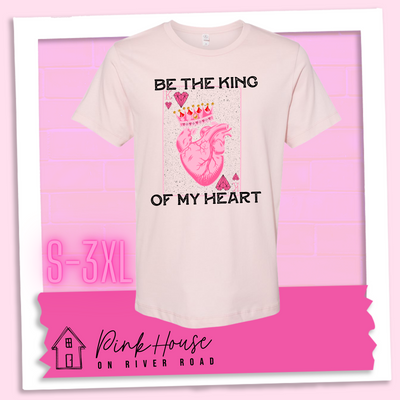 Faded Pink Jersey Tee with a graphic that says "Be The King Of My Heart" in Black writing with a vintage effect. There is a King PLaying card with a speckled background, geometric hearts in the corners with the K and a realistic heart with a crown on it in the middle of the playing card.