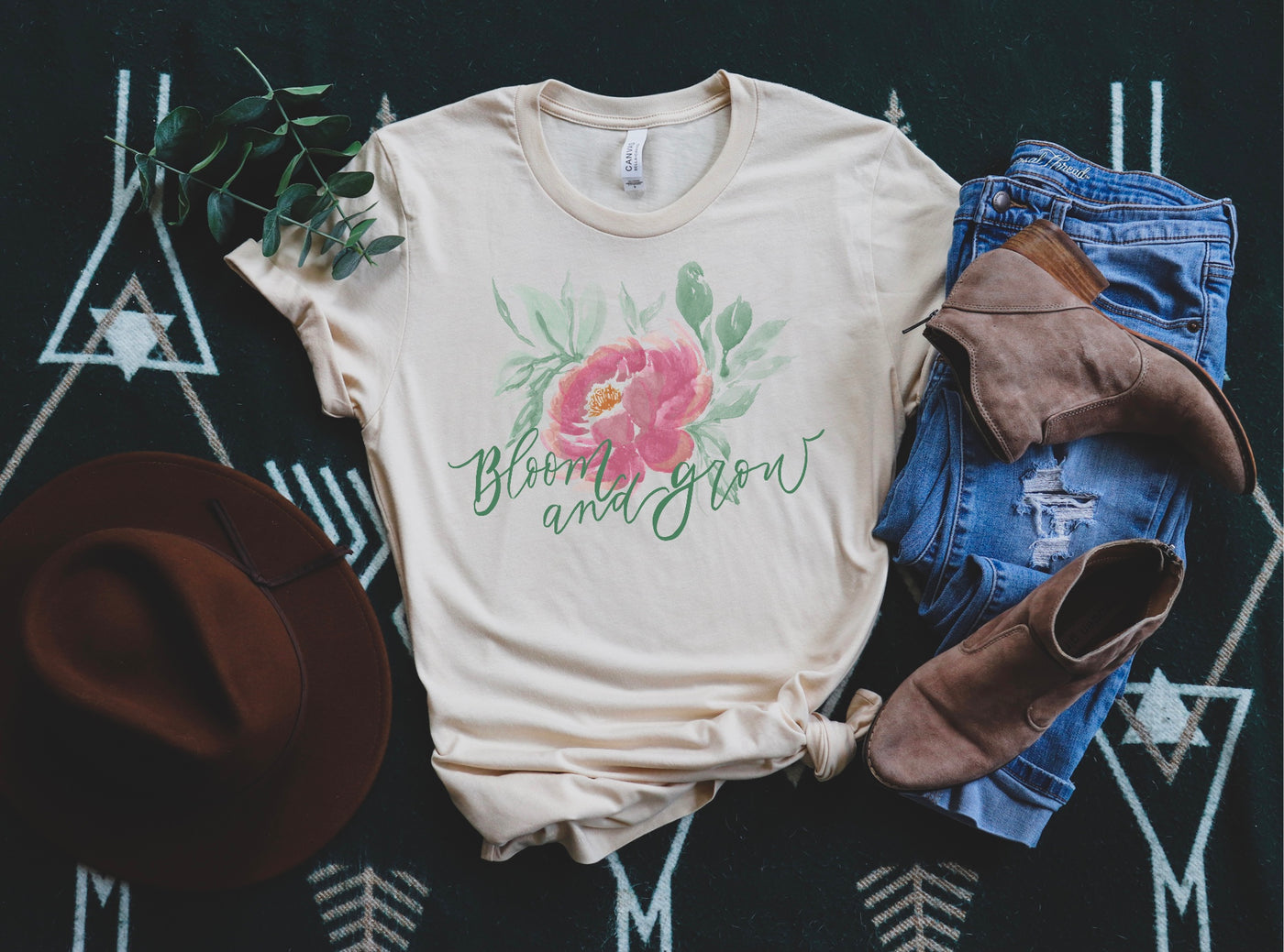Baby pink Tee with graphic has a watercolor style pink flower with green leaves and the words Bloom and Grow in green.
