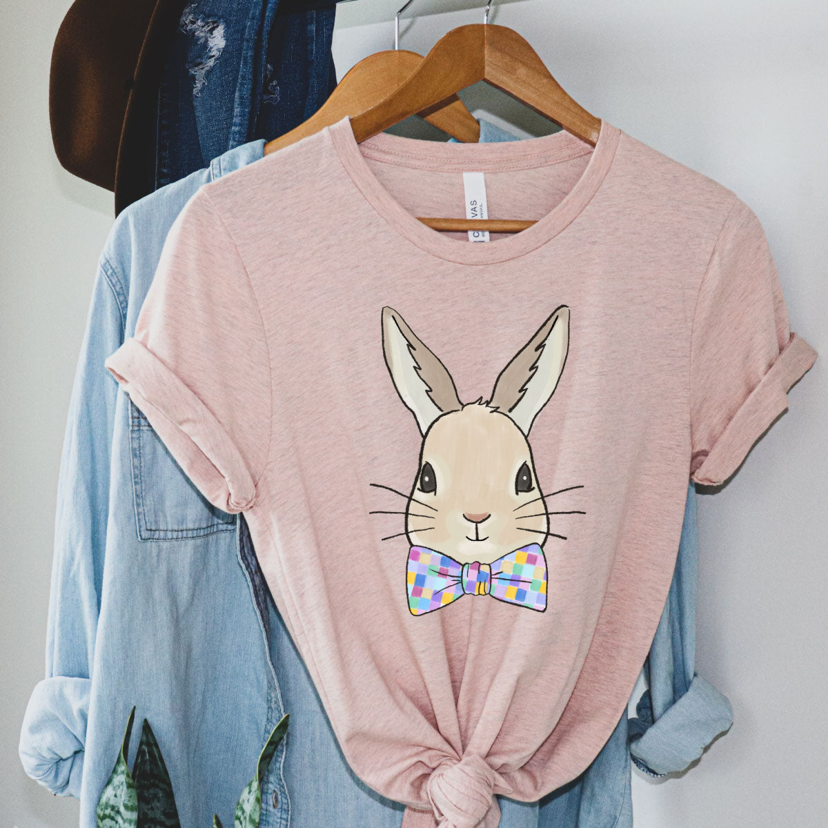 Heather pink tee with a graphic of a bunny wearing a bowtie with multicolored squares on it