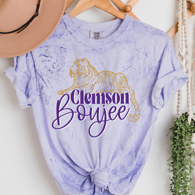 Purple Colorblast tee with a gold line drawing tiger laying on top of the words Clemson Boujee. The text is purple with a white shadow and the word boujee is in cursive