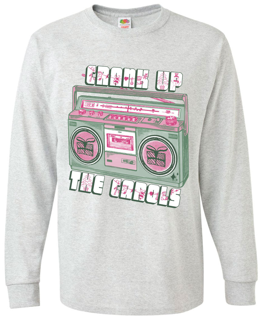 Ash gray long sleeve tee with graphic. Graphic has an old school boom box in the middle, the boom box is green with pink highlights and the speakers have the outline of presents on them. There is text above the boombox that is white with a green shadow and pink Christmas designs that says "Crank up" and below the boom box that says "The Carols"