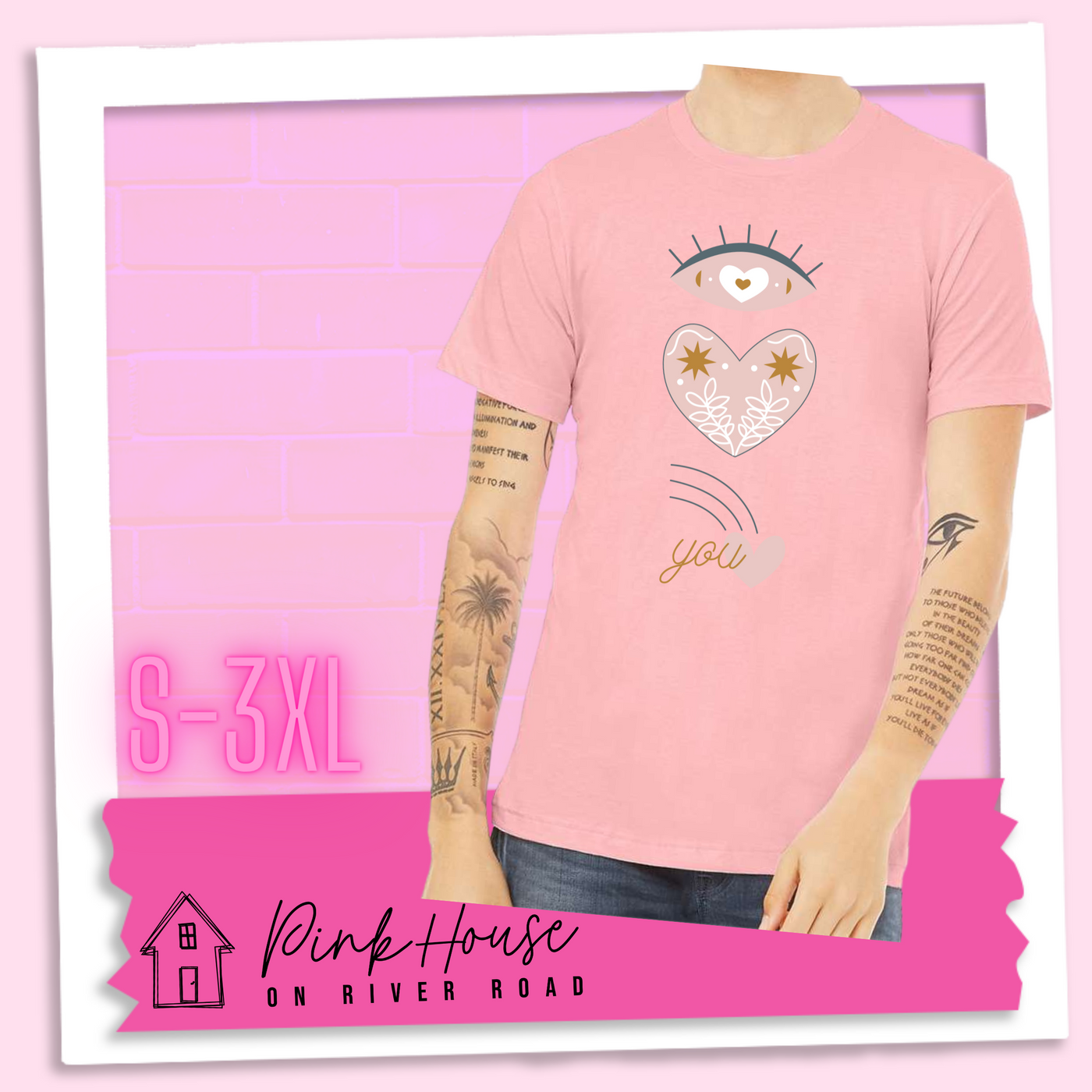Pink tee with a graphic of an eye with a heart for the pupil and underneath that a heart with a floral and star design and a shooting heart with the word you. The graphic represents eye heart you