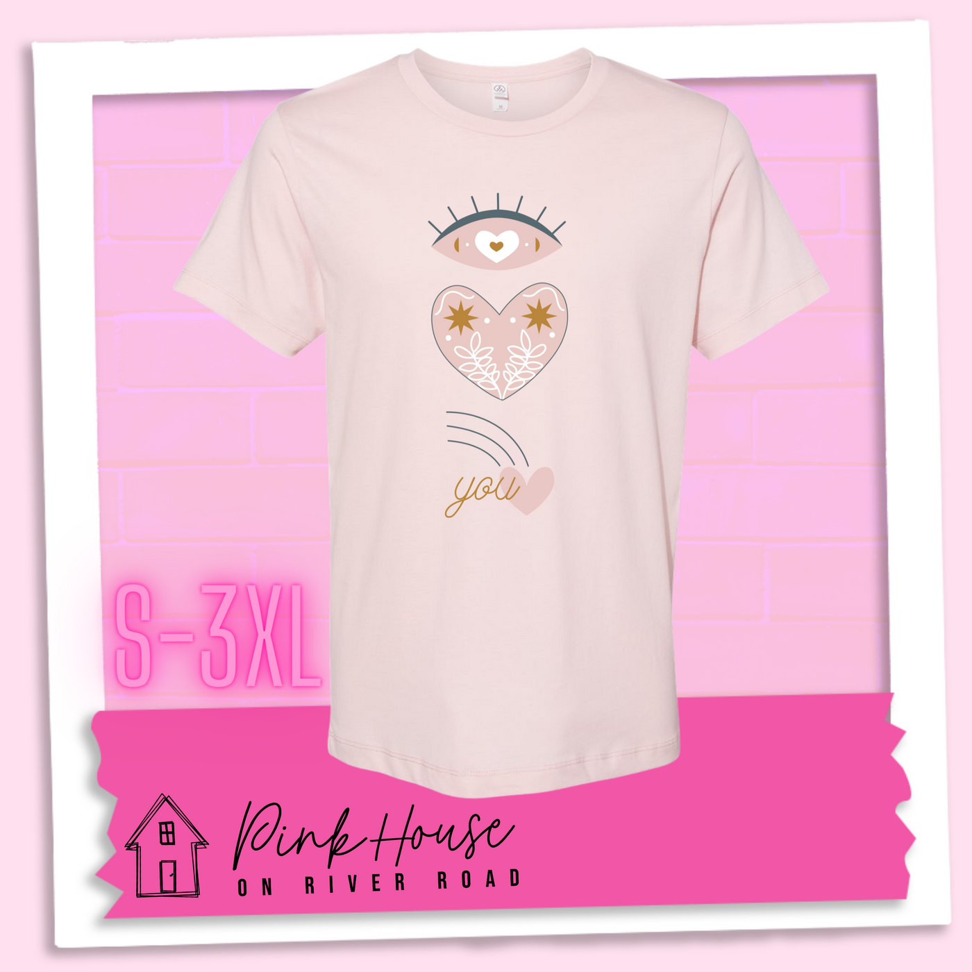 Faded pink tee with a graphic of an eye with a heart for the pupil and underneath that a heart with a floral and star design and a shooting heart with the word you. The graphic represents eye heart you