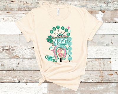 Cream Tee. Graphic of a vintage Neon Sign The word feeling with each letter in green circles at the top with the word lucky down the side with each letter in a turquoise circle. There is a sign in the center with the word motel in it, underneath there is a horse shoe with dice inside at he bottom of the sign. There is also a four leaf clover with the word clover city over it in green.