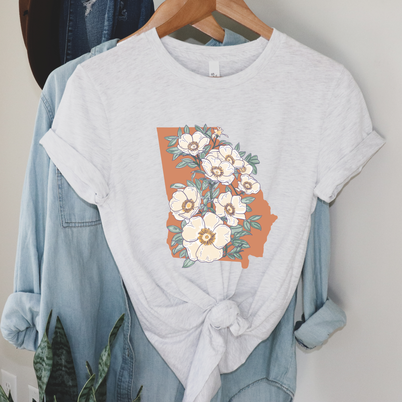 A grey tee with a graphic of the state of Georgia in peach covered with the state flower of Georgia.