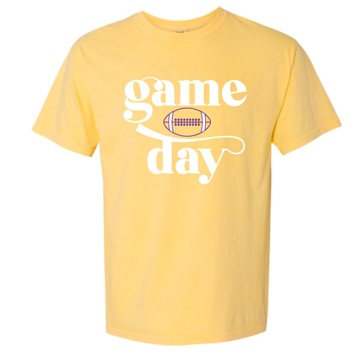 A yellow shirt with the word game stacked on top of a football stacked on top of the word day. The words are n white the football is in purple.
