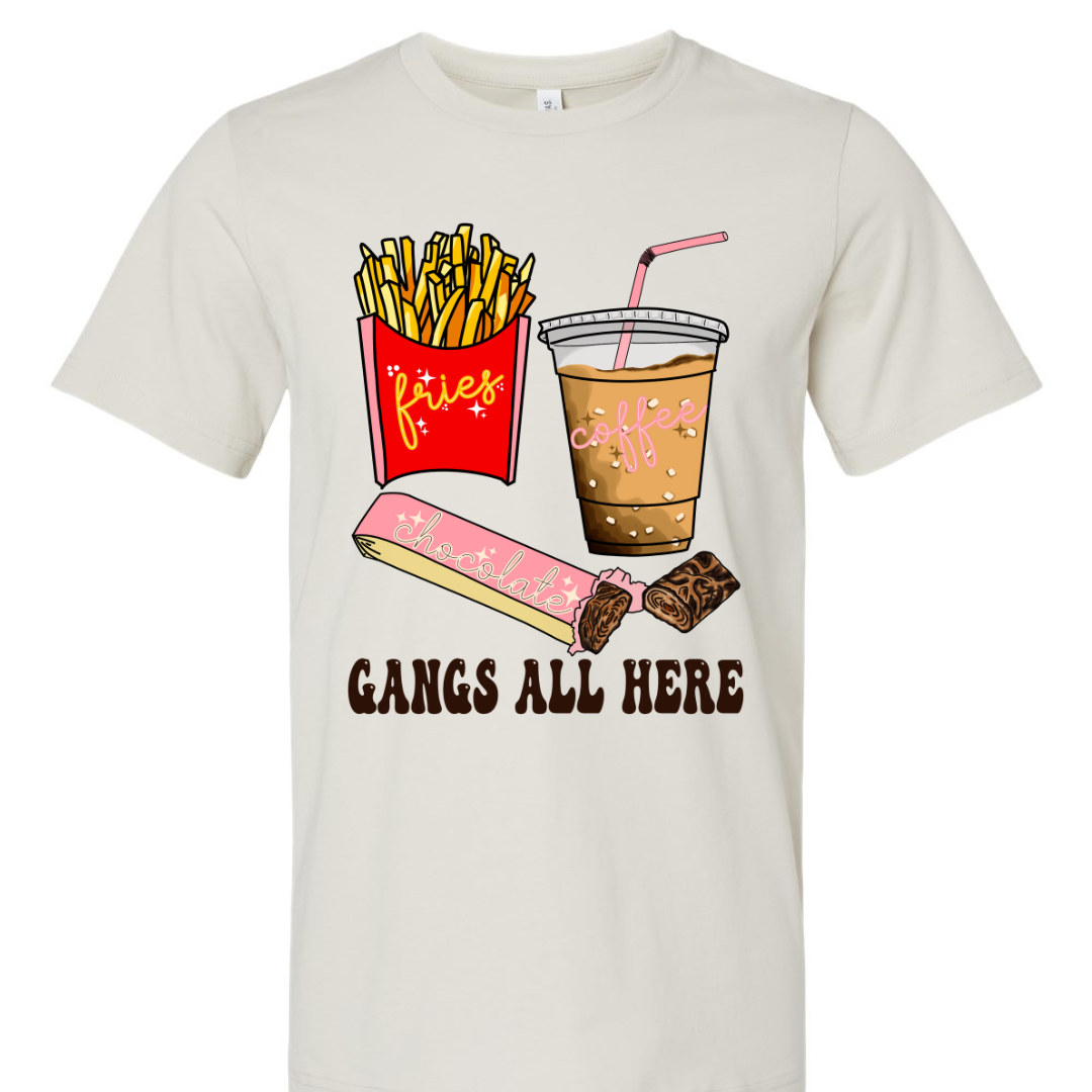 Dust shirt with graphic. Graphic is a container of fries with a yellow cursive font that says fries. A cup of iced coffee with a pink cursive font that says coffee and a chocolate bar witha pink wrapper and a blue cursive font that says chocolate. Under the food there is a black bubble font that says gangs all here.