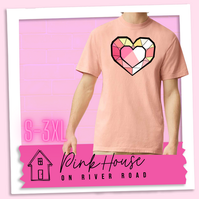 Peach graphic tee. the graphic is of a geometric heart, it has black outlines to make it look like a gem with different shades of pinks, yellows, and white.
