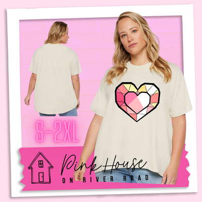 A blonde woman wearing a oversized cream HiLo graphic tee. the graphic is of ageometric heart, it has black outlines to make it look like a gem with different shades of pinks, yellows, and white.
