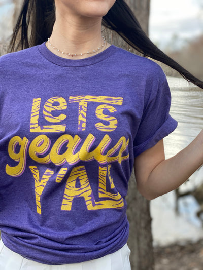 Heather Purple shirt with the word Lets Geaux Y'all stacked vertically. Lets and Y'all are yeallo with purple tiger stripes and the word geaux is yellow with a purple shadow.