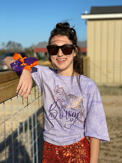 Brunette model wearing a Purple Tie Dye Shirt with a gold foil tiger and the words Clemson Boujee in purple with a white shadow under the tiger.