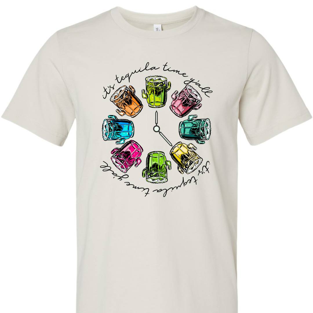 Dust tee with a graphic. Graphic has a clock in the center with multicolored margaritas instead of numbers and around the outside of the clock are the words "It's tequila time y'all" in black cursive font.