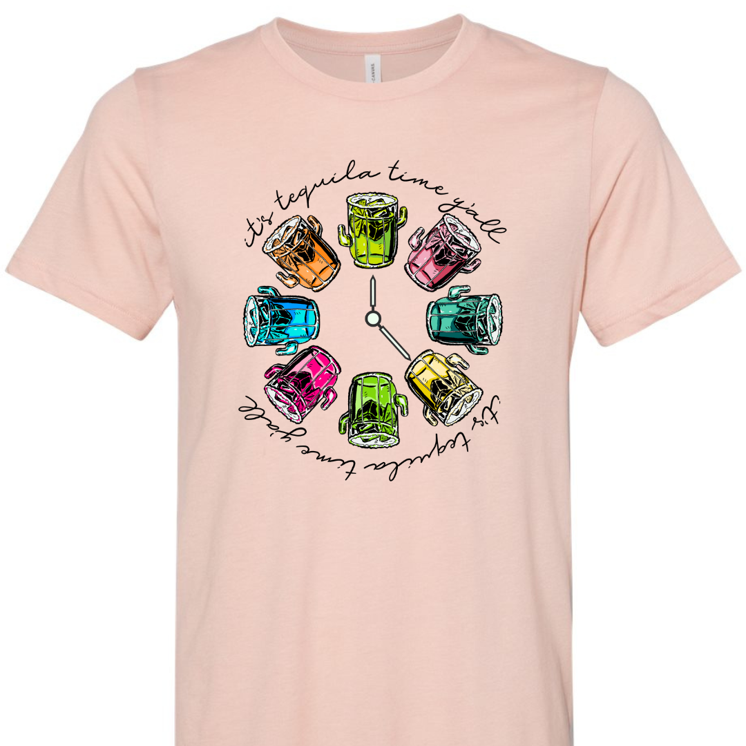 Soft Pink tee with a graphic. Graphic has a clock in the center with multicolored margaritas instead of numbers and around the outside of the clock are the words "It's tequila time y'all" in black cursive font.