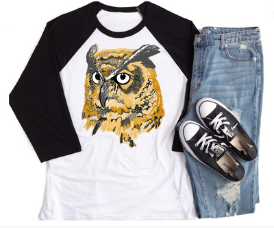 White raglan with black sleeves with a graphic of a yellow, orange and gray layered owl