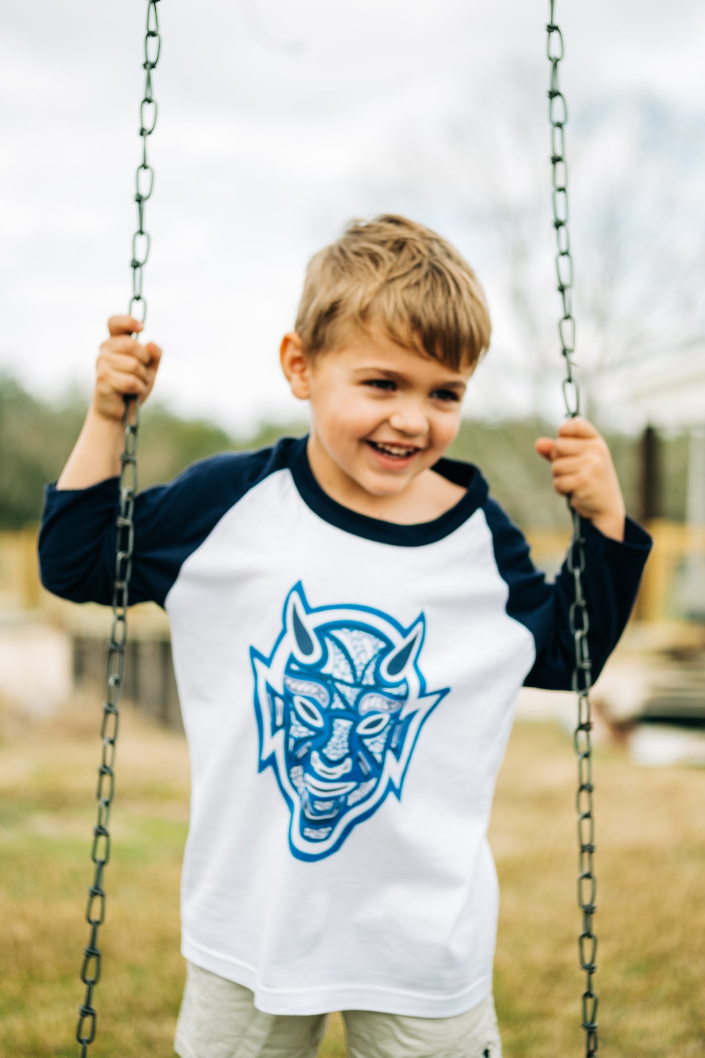 White with navy sleeves raglan tee with a graphic of a devil layered with different designs and different shades of blue