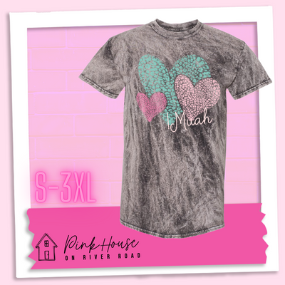 Charcoal Mineral wash tee with 3 different colored leopard print hearts in various sizes in the lower right hand corner of the graphic is the word Muah in light punk script