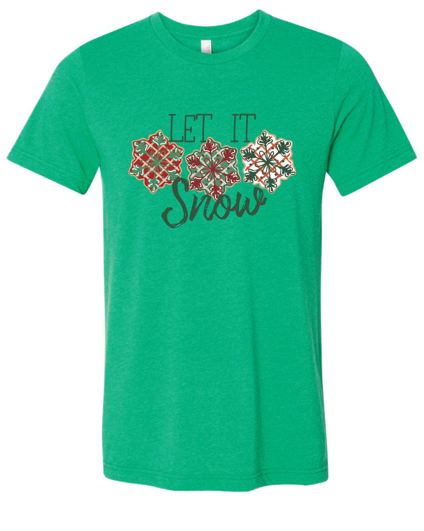 Green tee with the words Let It in think block letters at the top with three snowflakes underneath. Far left snowflake is red with beige stripes and a green snowflake design on the top, Middle snowflake is green with white stripes and a dark red snowflake design on the top, and the right snowflake is white with red stripes and a dark green snow flake design on top and the word snow in a brush script underneath.