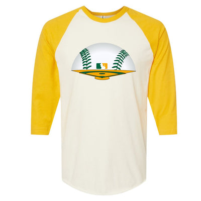 Yellow and White Raglan. Graphic is a green and yellow baseball field The horizon is a baseball with green laces and there is a baseball symbol in yellow and green with a lion in the middle near center field.