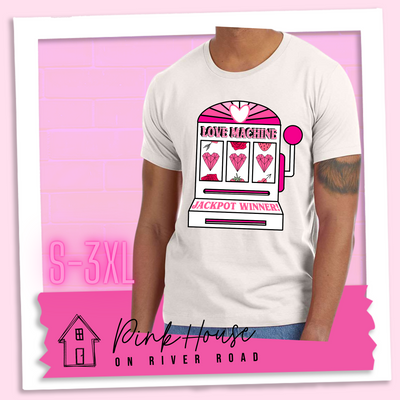 Dust Tee with a graphic. Graphic is of a white slot machine with pink accents at the top of the slot machine is an arch with different shades of pink and a heart cut out of the middle. Underneath the are are the words Love machine in hot pink with white dots to look like lights. the reels of the slot machines show three geometric hearts. The slot pull has a pink base with a white handle and pink knob on it. Under the reels are the words Jackpot Winner in pink.