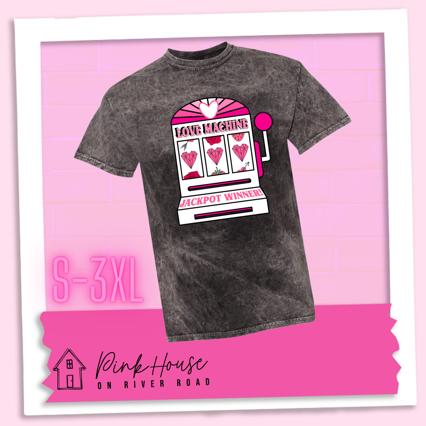 Black Mineral Wash Tee with a graphic. Graphic is of a white slot machine with pink accents at the top of the slot machine is an arch with different shades of pink and a heart cut out of the middle. Underneath the are are the words Love machine in hot pink with white dots to look like lights. the reels of the slot machines show three geometric hearts. The slot pull has a pink base with a white handle and pink knob on it. Under the reels are the words Jackpot Winner in pink.
