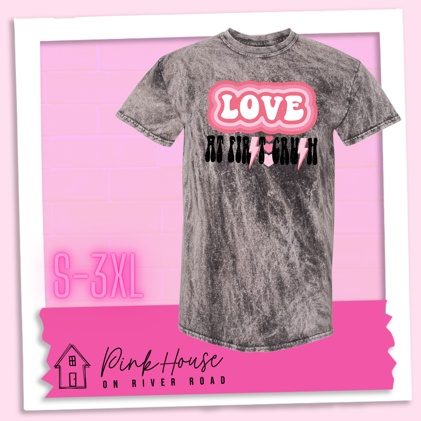 Charcoal Mineral Wash Tee. The graphic has the word Love in retro bubble letters with differetn colored pink outlines radiating from the word, underneath are the worxs at first in black with the s in first replaced with a pink lightning bolt, then there are three different colored hearts followed by the word crush in the same black font with the S replaced with the same pink lightening bolt.