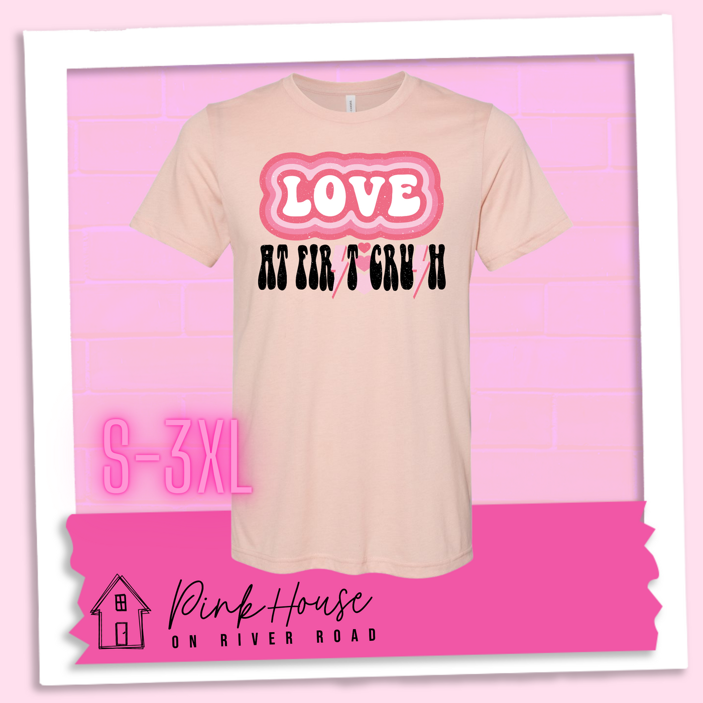 Heather Peach Tee. The graphic has the word Love in retro bubble letters with differetn colored pink outlines radiating from the word, underneath are the worxs at first in black with the s in first replaced with a pink lightning bolt, then there are three different colored hearts followed by the word crush in the same black font with the S replaced with the same pink lightening bolt.