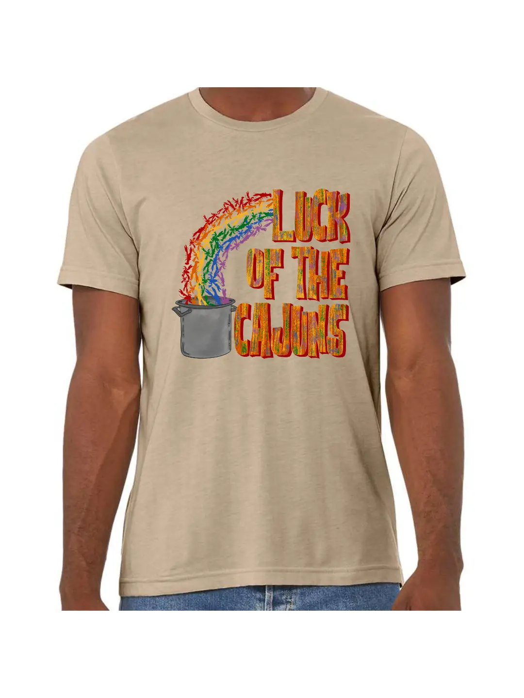 A Heather Tan tee with a graphic. Graphic has the words Luck of the Cajuns on the right the words are in a block font with a muted rainbow. To the left there is a rainbow of crawfish ending in a large boiling pot.