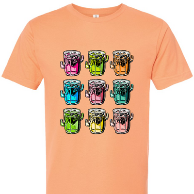 A cantaloupe tee with a graphic. Graphic is of 9 margarita glasses, 3 rows of 3, all shaped like cactus with ice cubes, limes and salt on the rim, all 9 glasses are a different color.