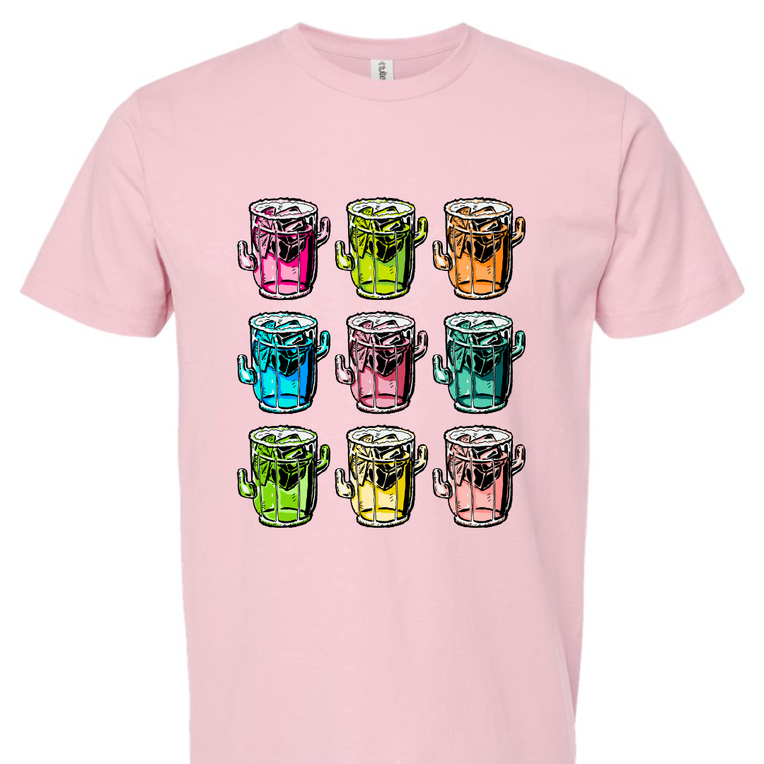 A soft pink tee with a graphic. Graphic is of 9 margarita glasses, 3 rows of 3, all shaped like cactus with ice cubes, limes and salt on the rim, all 9 glasses are a different color.