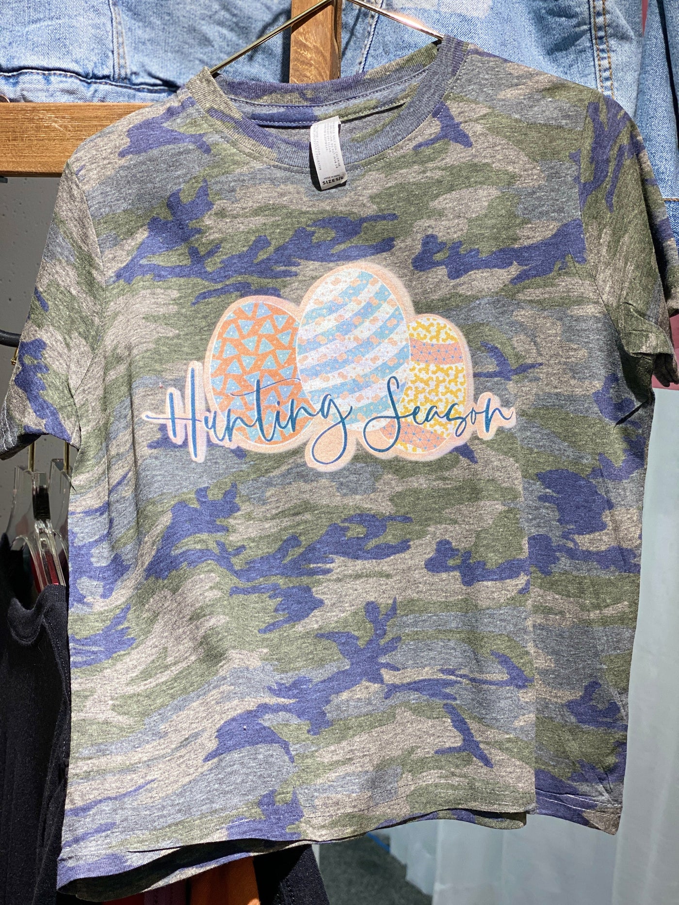Heathered camo tee with a graphic of three differently decorated easter eggs and the words "Hunting Season" In a blue cursive font