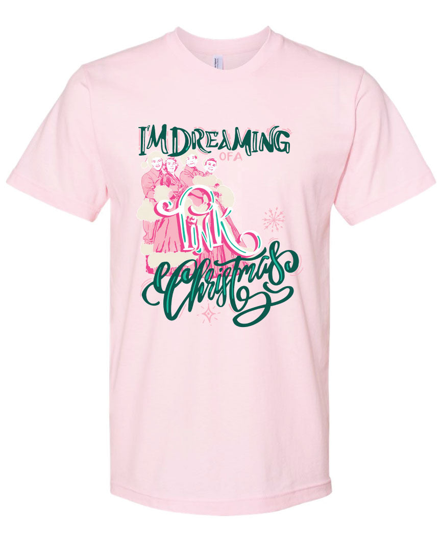 Pink tee with the words Im Dreaming in a green whimsical font underneath there is the wors of a in a pink color there is a graphic of two couples in vintage winter clothing and the word Pink over the couple and the word Christmas at the bottom in the same green font as the words im dreaming