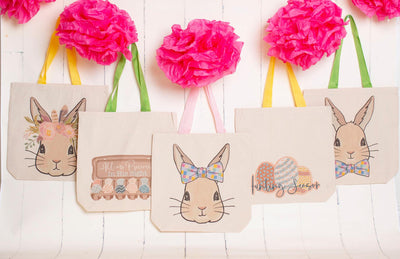 An image of 6 canvas easter totes. Far left: a bunny wearing a flower crown with yellow handles, 2nd to left: an egg carton with colored eggs all in a different design and the words all are precious in his sight on the lid. Middle: Bunny with a bow covered in multicolored squares. 2nd to right: # different colored easter eggs with the words hunting season in black cursive. Far Right: Bunny wearing a bow tie with multi colored squares on it.