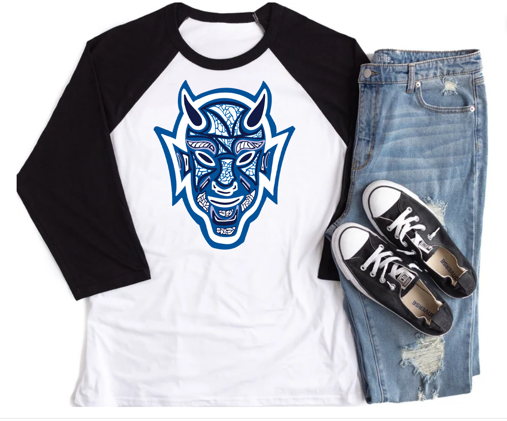 A white raglan with black sleeves and a graphic of a devil layered with different designs and different shades of blue